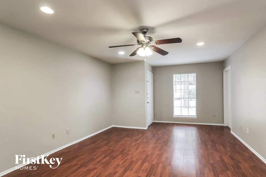 an empty living room with a ceiling fan and wood floors