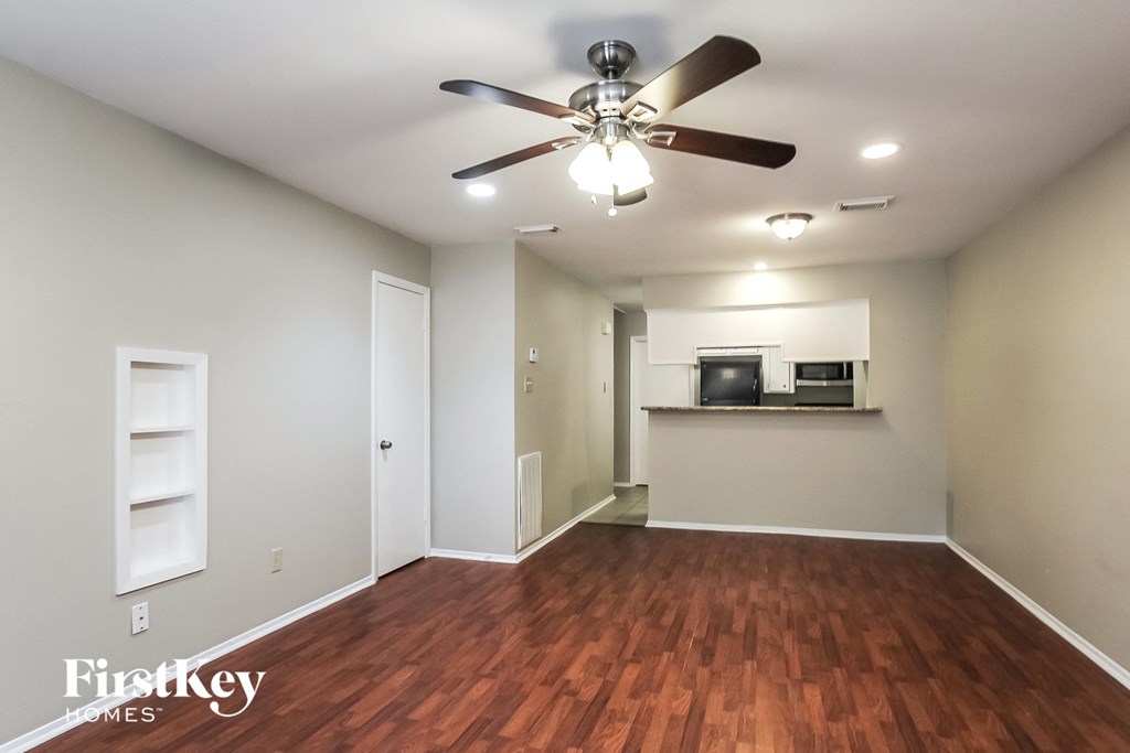 an empty living room with wood flooring and a ceiling fan
