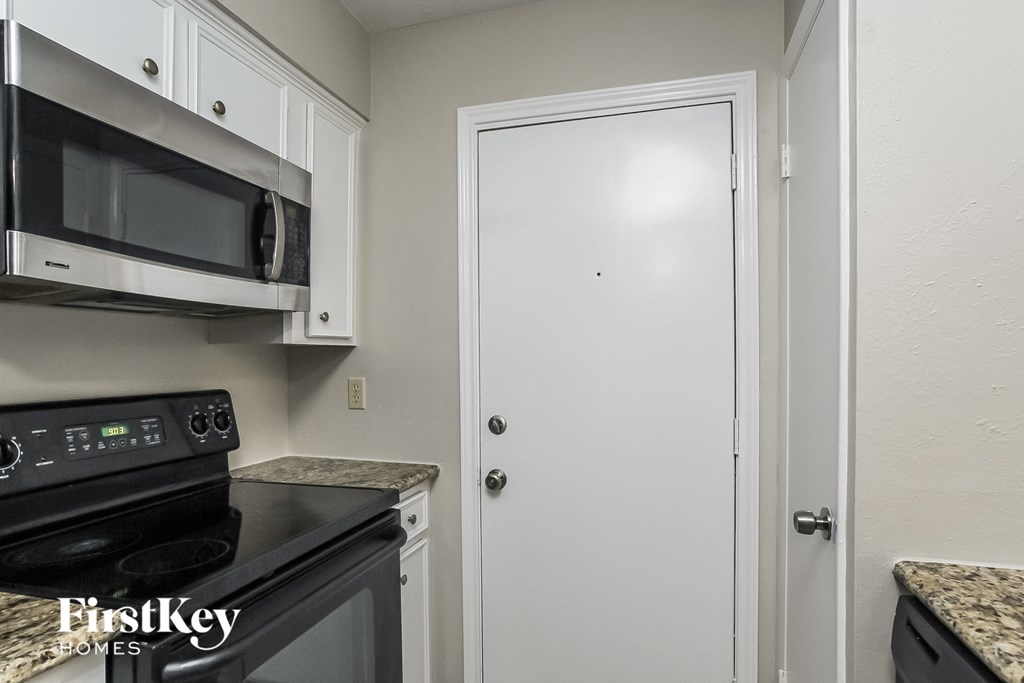 a kitchen with black appliances and white cabinets and a white door