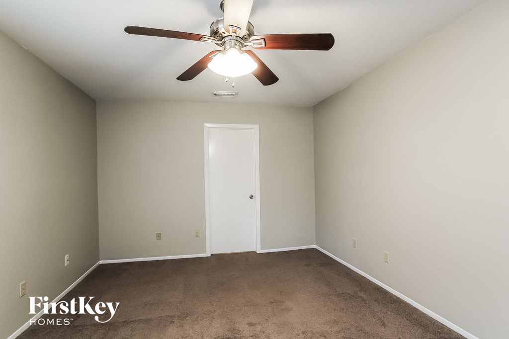 a empty room with a ceiling fan and a carpet