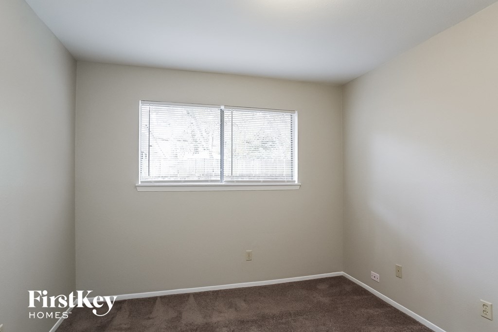 a bedroom with a window and a carpeted floor