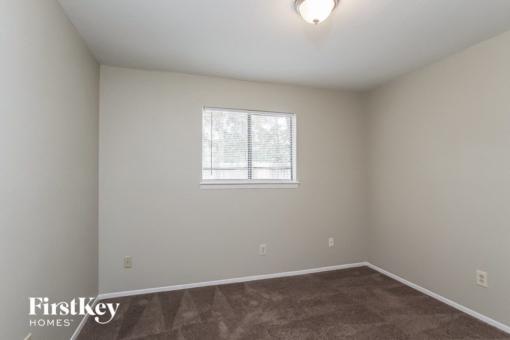 a bedroom with a window and a carpeted floor