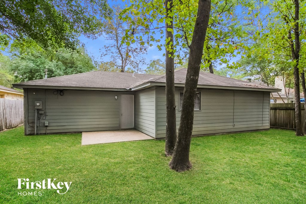 a small gray house in a backyard with grass and trees