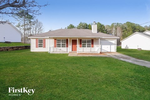 the front view of a white house with red doors and a lawn