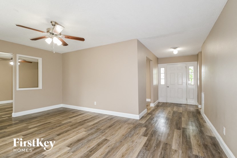 the spacious living room with wood flooring and a ceiling fan