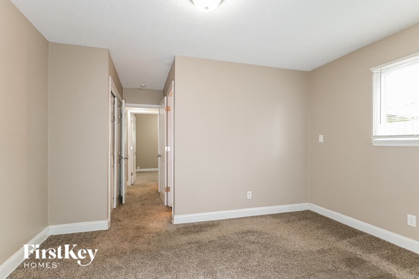 a bedroom with a carpeted floor and a door to a hallway