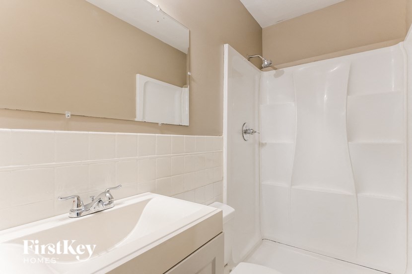 a white bathroom with a sink and a shower