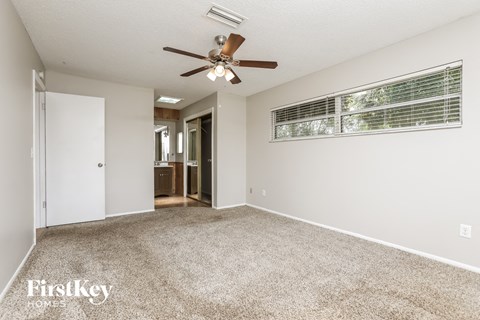 a spacious living room with carpet and a ceiling fan