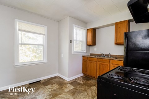 A kitchen with a black stove top oven and wooden cabinets.