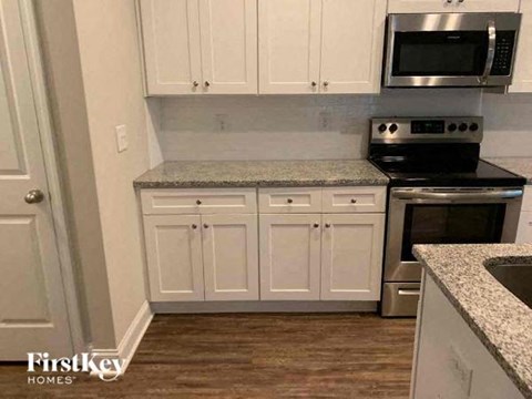 A kitchen with white cabinets and a granite countertop.