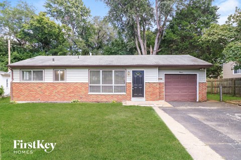 A house with a red brick wall and a brown garage door is for sale.