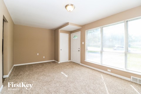 A room with a carpet floor and a window with blinds.