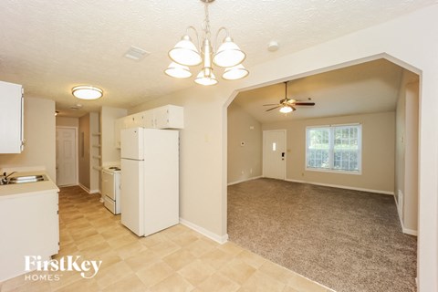 a kitchen and living room with a white refrigerator and a ceiling fan