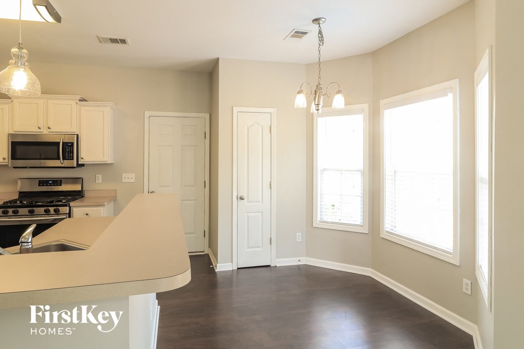an empty kitchen and living room with white cabinets and a window