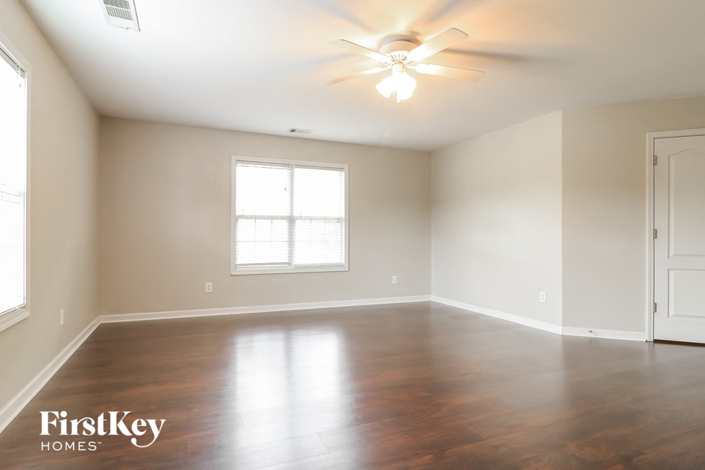 an empty living room with wood floors and a ceiling fan