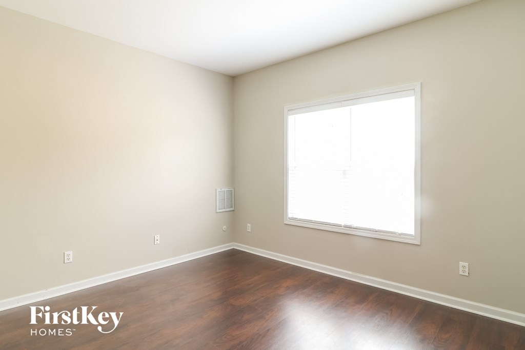 an empty room with a window and wood floors