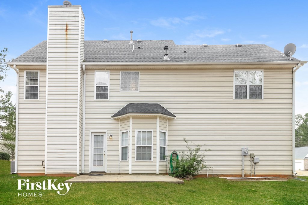 a white house with a gray roof and a green lawn
