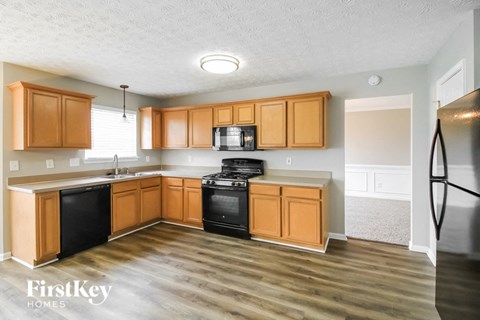 A kitchen with wooden cabinets and a black fridge.
