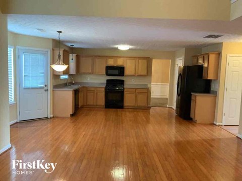 A kitchen with wooden floors and a black refrigerator.