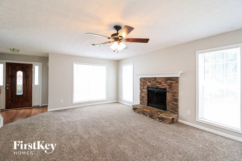 A spacious living room with a fireplace and a ceiling fan.