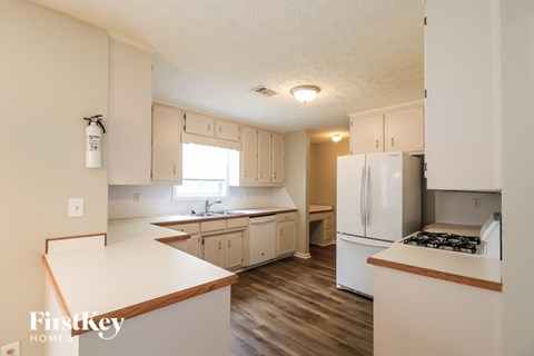 A kitchen with white cabinets and a wooden counter top.
