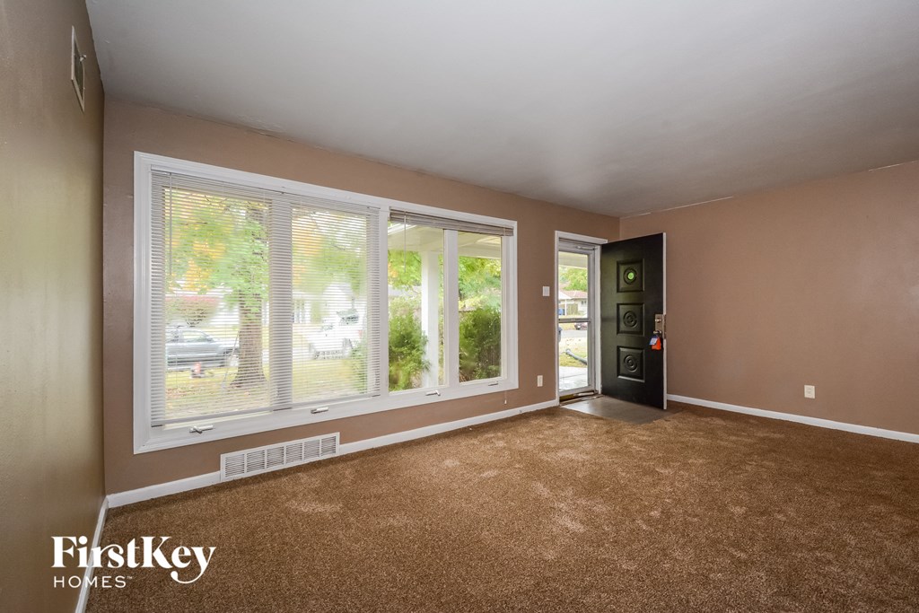 the living room of a house with large windows and carpeting