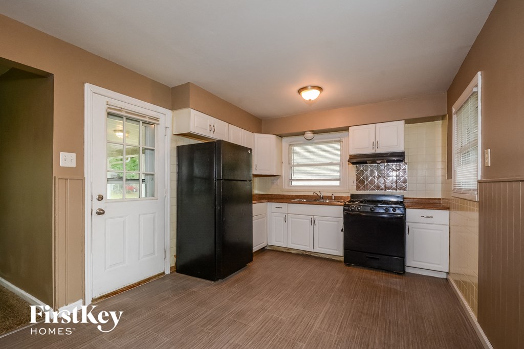 a kitchen with white cabinets and a black refrigerator