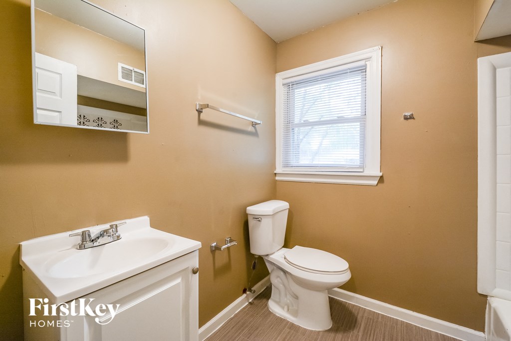 a bathroom with a toilet and a sink and a window