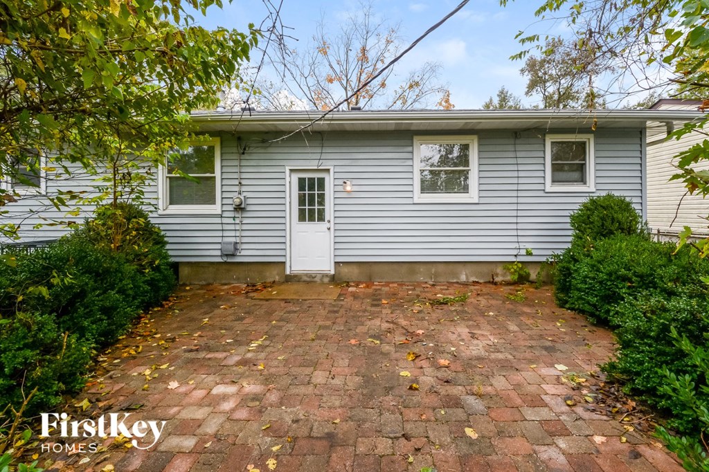 a blue house with a brick driveway and a white door