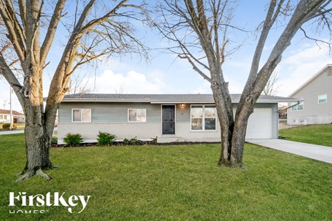 A house with a grey roof and a tree in front of it.