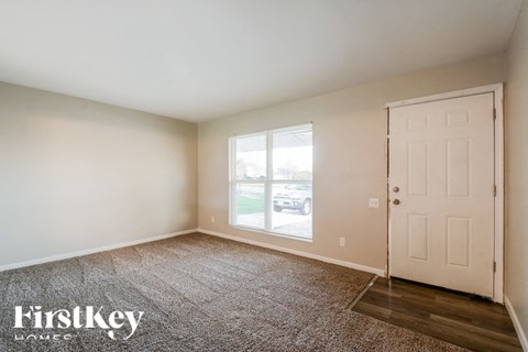 A room with a carpeted floor, a door, and a window.