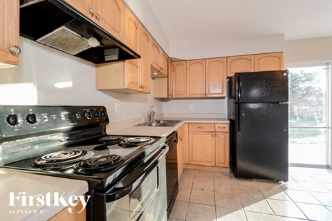 A kitchen with a black refrigerator and a stove with a glass top.
