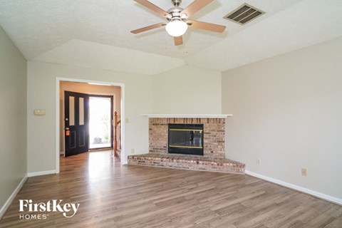 A living room with a fireplace and a ceiling fan.