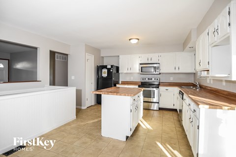 A kitchen with white cabinets and a wooden island.
