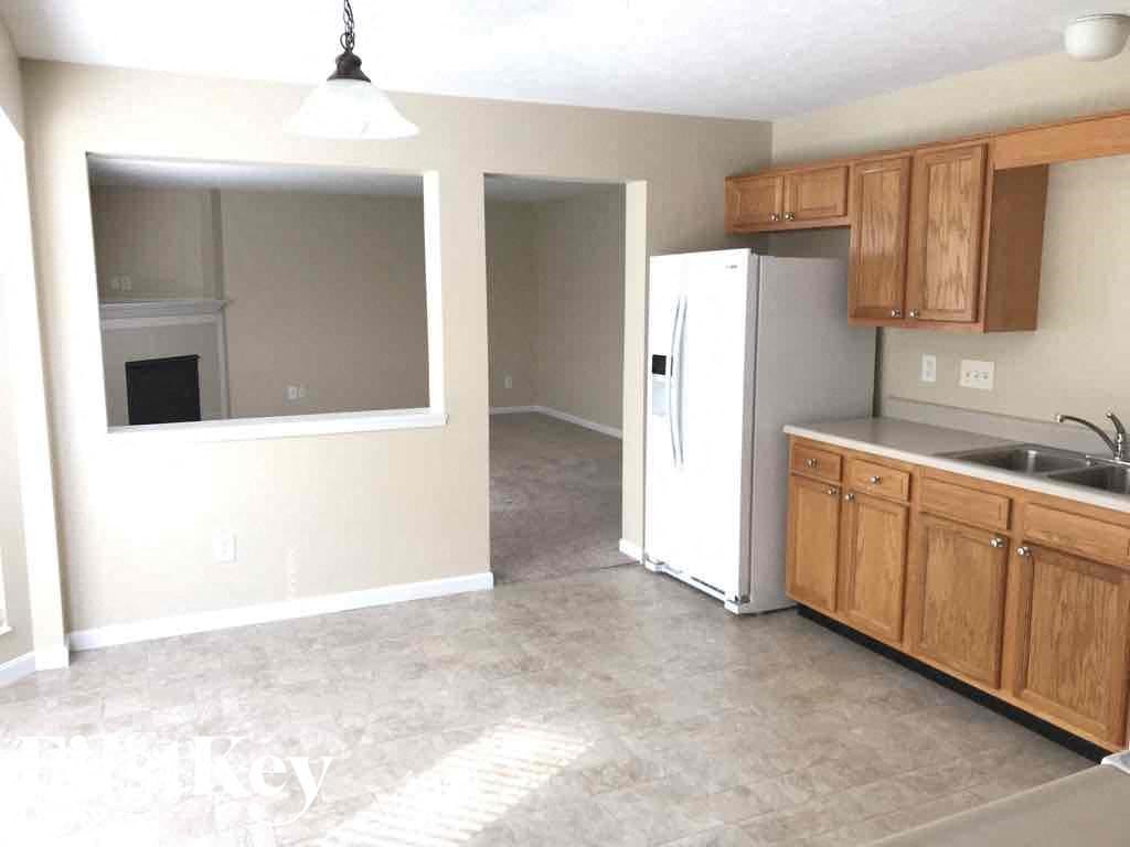 an empty kitchen with wooden cabinets and a refrigerator