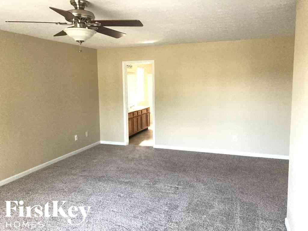 an empty living room with carpet and a ceiling fan