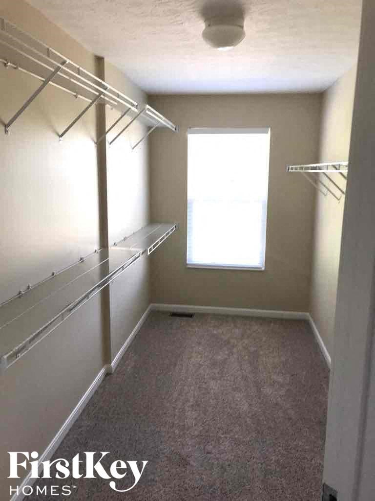 a walk in closet with empty shelves and a window