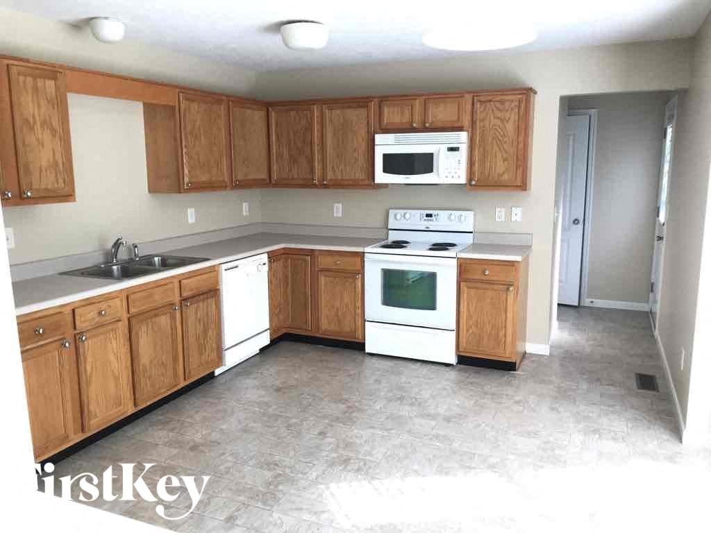 an empty kitchen with white appliances and wooden cabinets