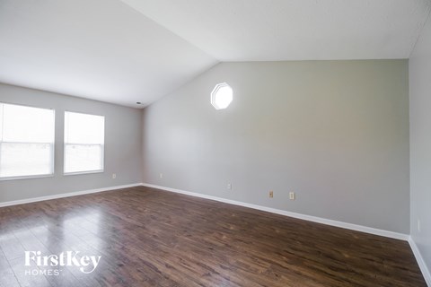 the spacious living room with wood floors and white walls