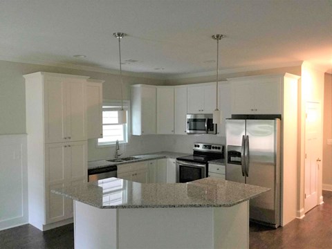 A kitchen with a granite countertop and stainless steel appliances.