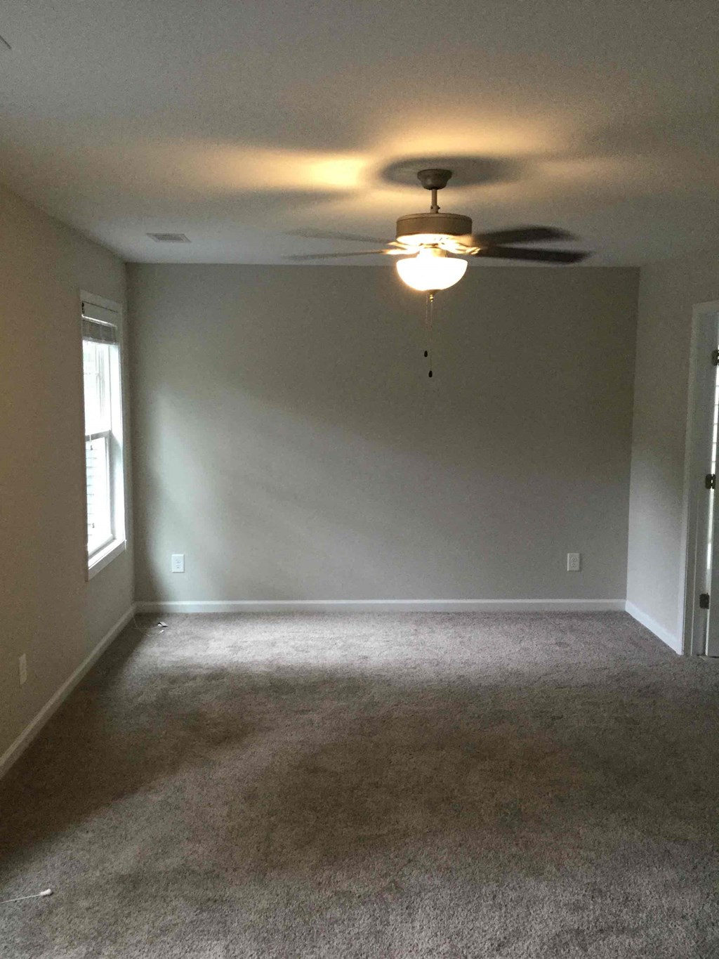 A room with a ceiling fan and carpeted floor.