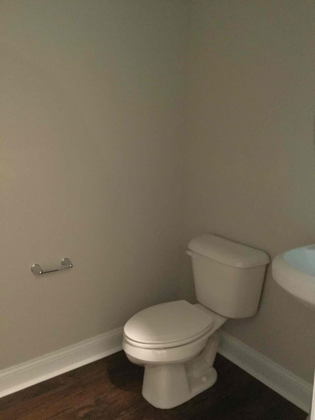 A white toilet in a small bathroom with a white toilet paper holder.