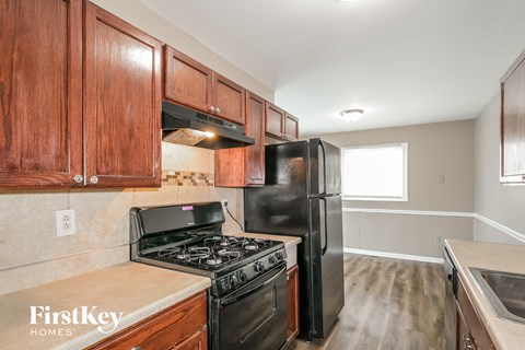 A kitchen with wooden cabinets and a black refrigerator.