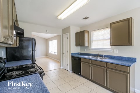 A kitchen with a black fridge and stove top oven.