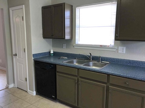 A kitchen with brown cabinets and a black dishwasher.