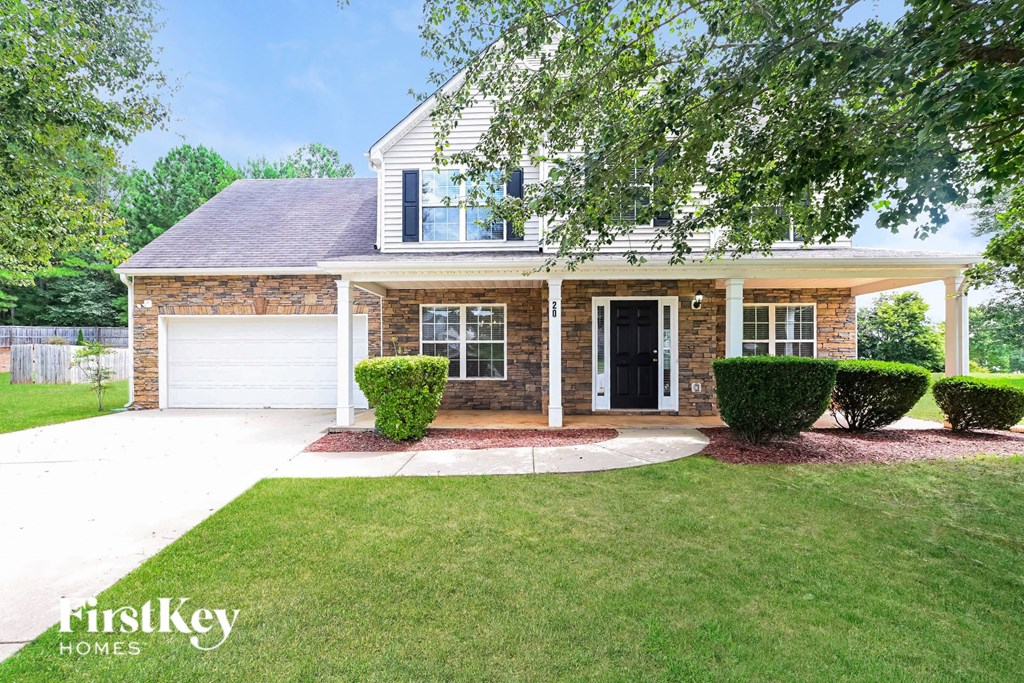 a brick house with a lawn and a white driveway