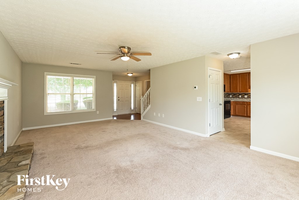 an empty living room and kitchen with a ceiling fan