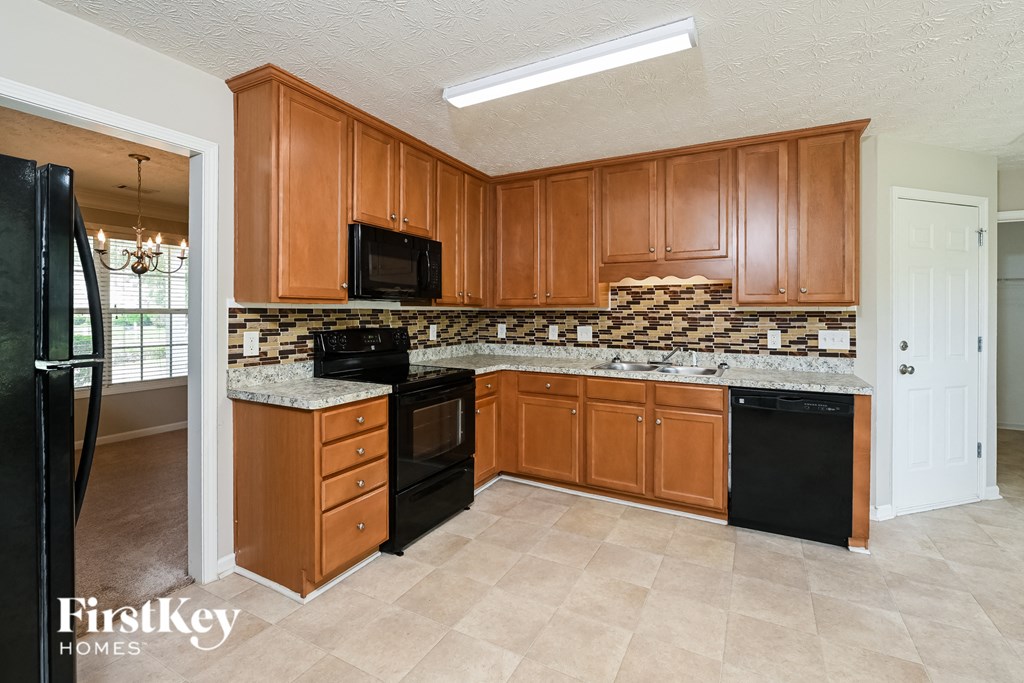 an empty kitchen with wooden cabinets and black appliances