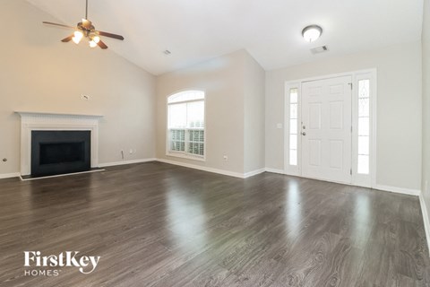 A spacious room with a fireplace and wood flooring.