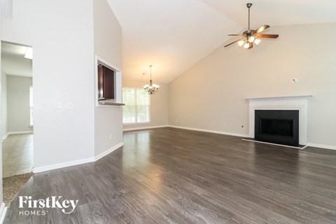 A spacious living room with a fireplace and a ceiling fan.